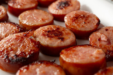 A closeup view of a layer of sauteed kielbasa slices, as a background.