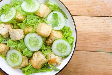 A plate of tofu salad on a wooden table with negative space.Healthy food.Meat substitute.