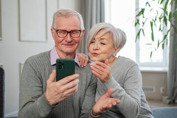 Video call. Happy senior couple woman man with smartphone having video call. Mature old grandmother grandfather talking speaking online. Older generation modern tech usage. Virtual meeting online chat