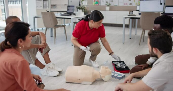 Office, first aid emergency and training people, explain and learning to use cpr equipment on dummy. Workplace, floor workshop and instructor speaking to group, medical support and paramedic coaching