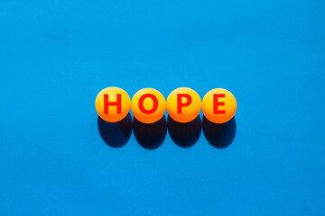 Hope symbol. Concept word Hope on beautiful yellow ping pong balls. Beautiful blue table blue...