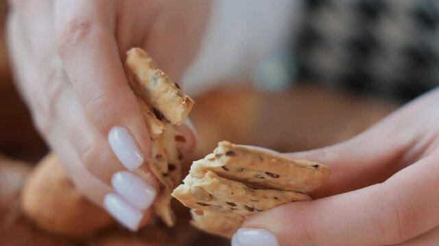 Hands breaking a seeded cracker, Close-up of hands breaking a crunchy cracker with seeds.