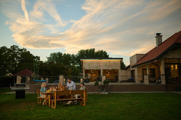 Family enjoying backyard barbecue dinner party at sunset