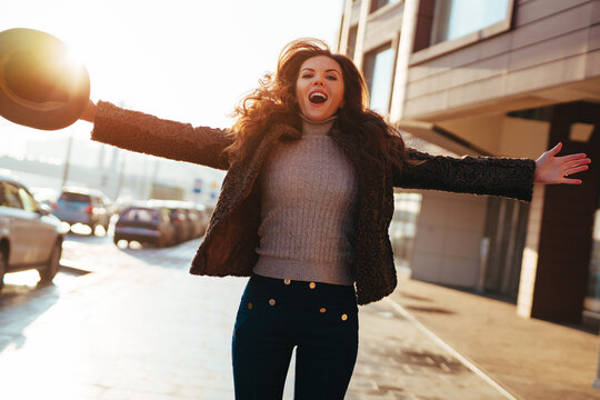 Young happy woman jumping on winter city street on winter sunny day