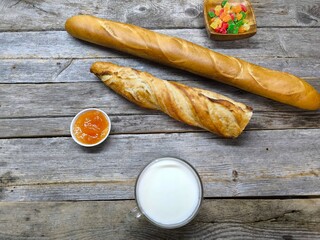 tasty pieces of baguette lie on a wooden table next to a cup of milk