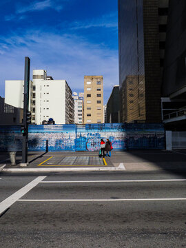 Cal&ccedil;ada e avenida com rua de pedestres com muro com grafite e pr&eacute;dios 