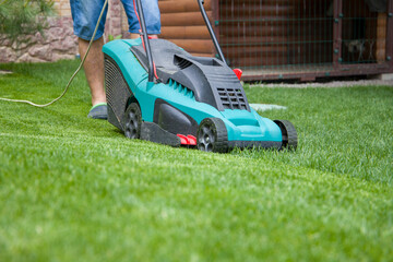Lawn mower cutting green grass in the garden. Gardening concept.
