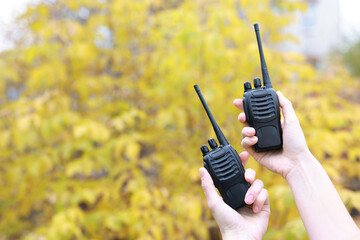 Woman with walkie talkies outdoors, closeup. Space for text