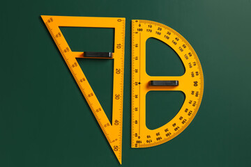 Protractor and triangle ruler on green chalkboard, top view