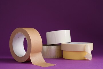Rolls of different adhesive tapes on purple background