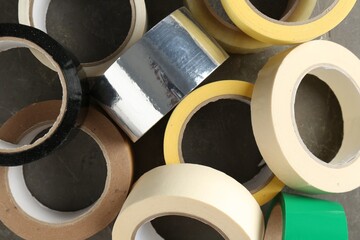 Rolls of different adhesive tapes on grey table, flat lay