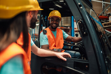 Warehouse workers talking near forklift in logistics center