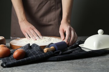 Woman with rolling pin and flour at grey table, closeup