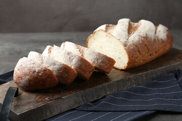 Cutting board with fresh bread on grey table, closeup