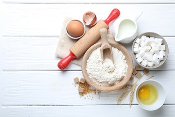 Rolling pin and ingredients for dough on white wooden table, flat lay. Space for text