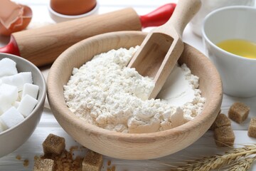 Ingredients for dough and rolling pin on white wooden table, closeup