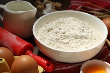 Rolling pin and ingredients for dough on table, closeup