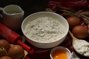 Rolling pin and ingredients for dough on table, closeup