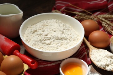 Rolling pin and ingredients for dough on table, closeup