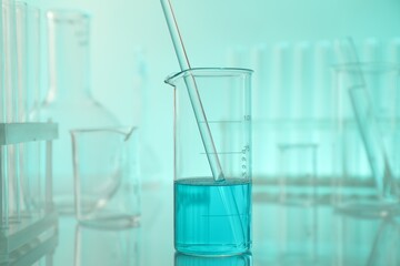 Laboratory glassware on mirror surface against turquoise background