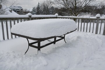 Snow accumulates on an outdoor patio table during a Canadian winter.