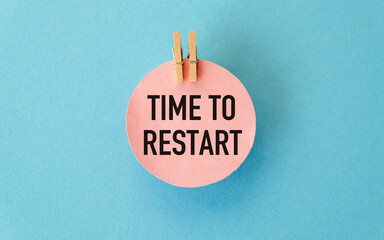 Time to Restart inscription on a round pink card on a blue background