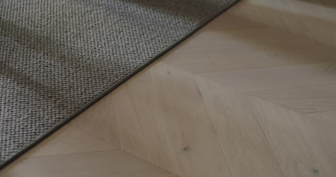 A minimalist image capturing bare feet walking on a wooden floor next to a carpet, evoking a sense of warmth and coziness in a home interior. Bare Feet Walking On Wooden Floor Next To Carpet
