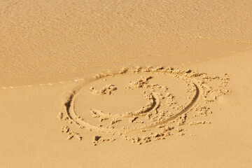 A painted smiley face on the beach sand