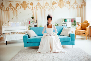 Elegant Woman in Historical Dress Sitting on a Sofa in a Luxurious Baroque Style Interior