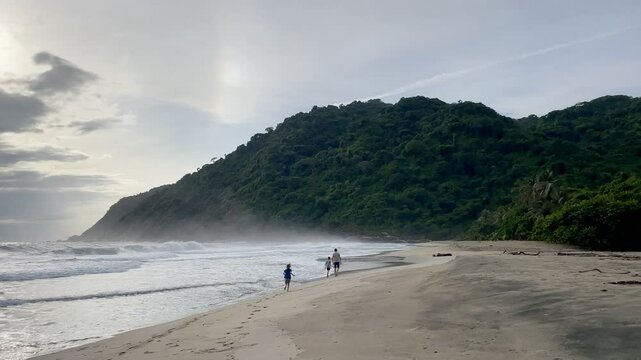 Family walking along Playa Brava at sunset, Tayrona National Park, Colombia.