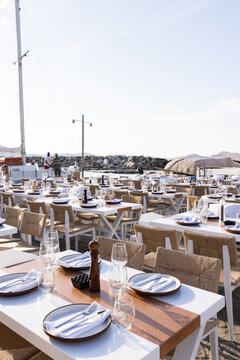 Outdoor seaside restaurants with tables set for dinner on Paros, Greece.
