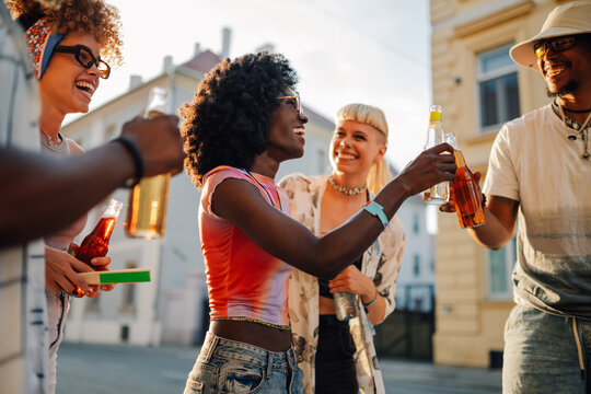 Friends toasting drinks at a festival, enjoying music and urban vibes