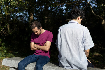 Obraz premium Gay couple arguing and feeling frustrated while sitting on a bench in a park