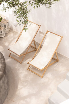 High angle view of white linen lounge chairs on a patio at a boutique luxury hotel in Santorini, Greece. 