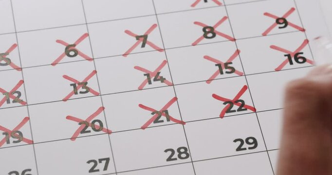 Hand marking calendar dates with red crosses. Represents planning, time management, and counting down days. Person Marking Calendar Dates With Red Crosses for Important Schedule Management