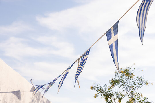Greek flags in the breeze against a blue sky in Santorini, Greece. 