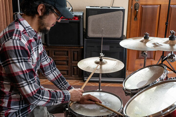 Drummer playing a drum set in a home studio