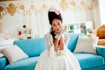 Elegant young woman in historical attire seated in a luxurious interior