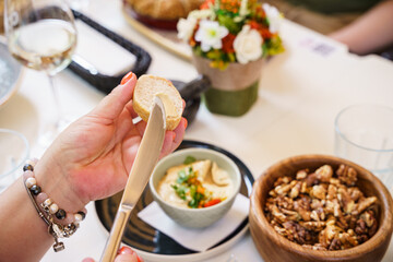 Spreading butter on bread at a table setting with dips and nuts
