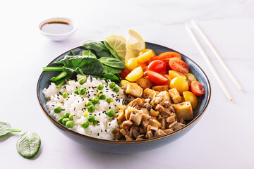 Fresh vegan bowl with cherry tomatoes, tofu, white rice, spinach leaves, fried mushrooms and green pea on white background close up. Healthy diet food concept. 