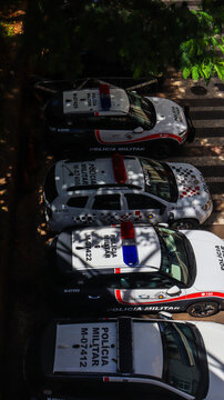 Viaturas da pol&iacute;cia estacionadas sob a sombra de uma &aacute;rvore. Ve&iacute;culos oficiais alinhados, ambiente urbano, seguran&ccedil;a p&uacute;blica e patrulhamento policial. S&atilde;o Paulo SP 12 02 25