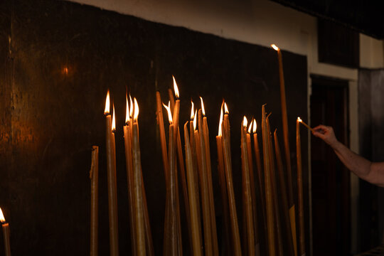 Hand lighting religious prayer candles in Greek Orthodox church in Tinos, Greece.