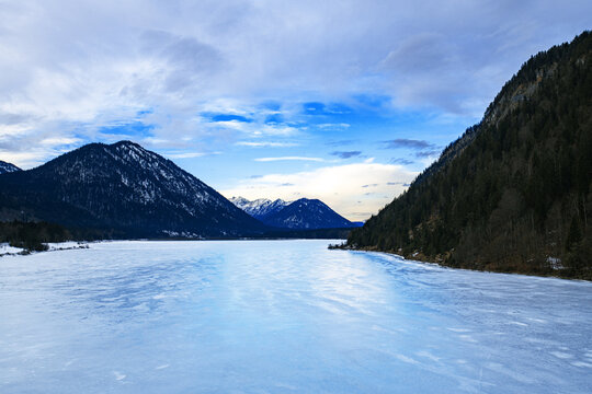 Winter landscape of mountains, fozen lake and cloudy blue sky