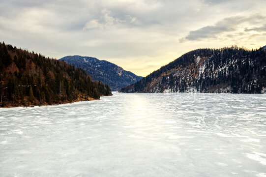 Winter landscape of mountains, fozen lake and cloudy blue sky