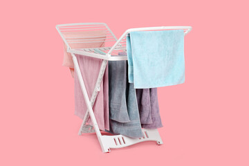 Drying rack with fresh clean laundry on light pink background