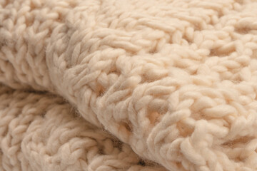A fragment of beige knitted fabric, knitted from white sheep wool.