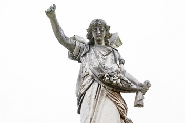 Fototapeta premium Weathered angel statue with raised arm in a cemetery setting