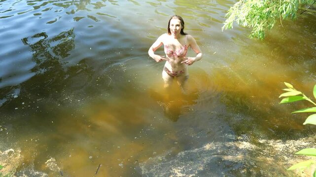 Young woman in lingerie swims in cold dirty water. Slow motion erotic portrait woman. Woman naked posing standing in water