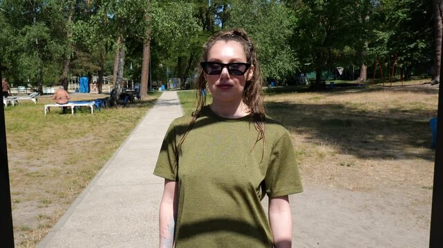 Portrait young woman in green t-shirt in sunglasses walking. Sporty woman. slow motion portrait