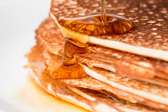 Close-up of maple syrup being poured on a stack of pancakes 